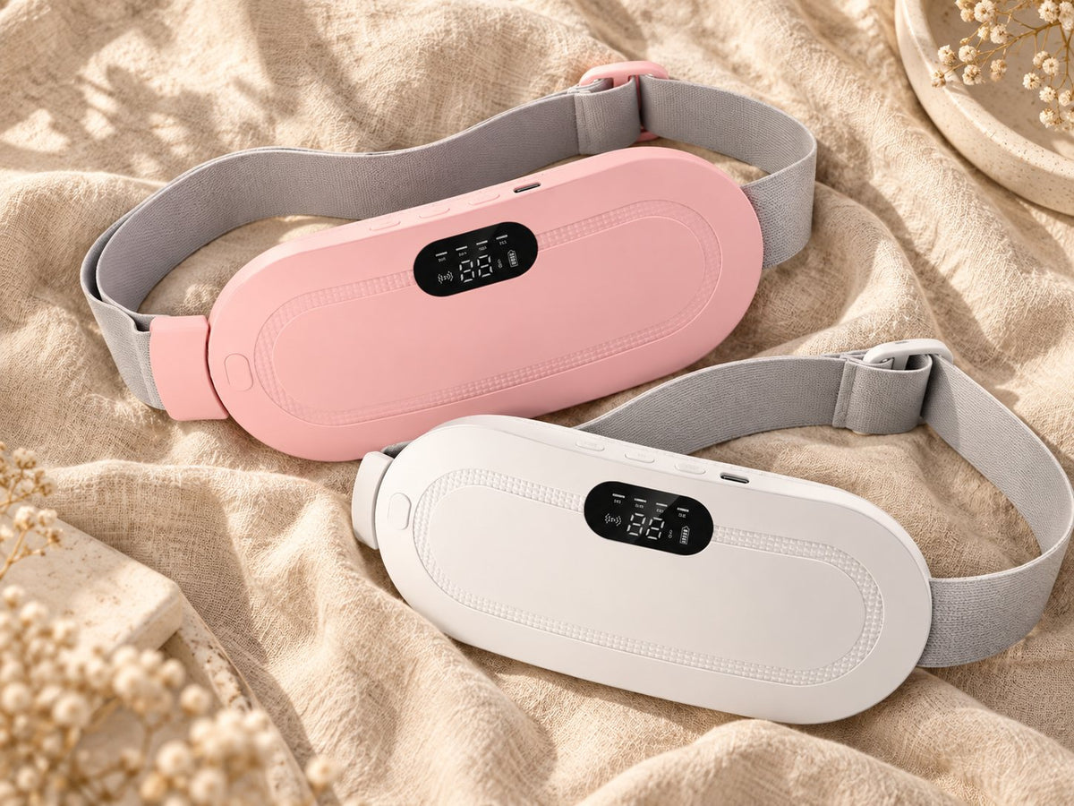 Ceinture chauffante Calya en rose et en blanc, posées à plat sur un plaid sable