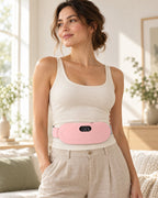 Femme portant la ceinture chauffante Calya rose autour de la taille dans un salon lumineux
